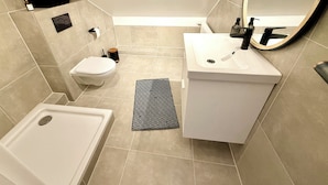 A modern bathroom with a toilet, sink, and bathtub. - Rooftop Lounge Studio Apartment directly at the University Hospital Homburg (Homburg)