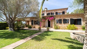 A stone house with a garden, a large tree, and a clear sky. - Es Molí: Views, Mallorca Essence and Private pool (Santa Eugènia)