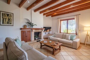 A living room with a fireplace, a sofa, a coffee table, and a television. - Es Molí: Views, Mallorca Essence and Private pool (Santa Eugènia)