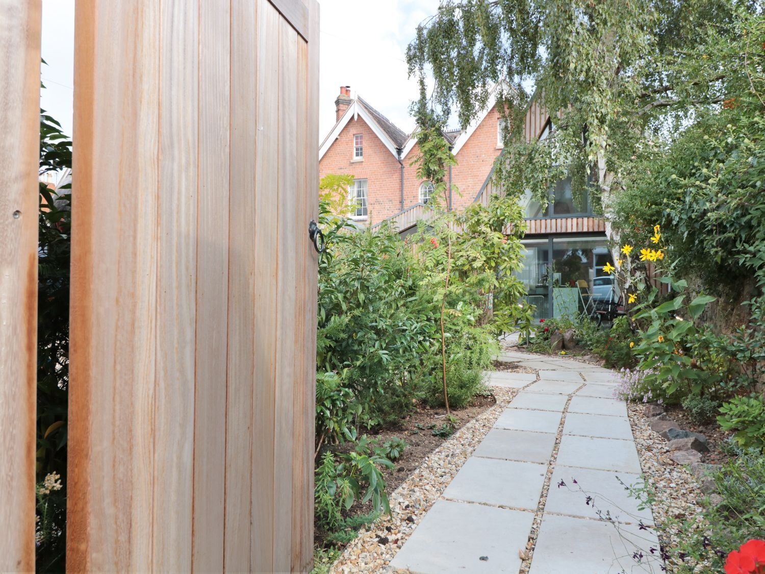 Un sendero en un jardín que conduce a una casa de ladrillo con diseño moderno.