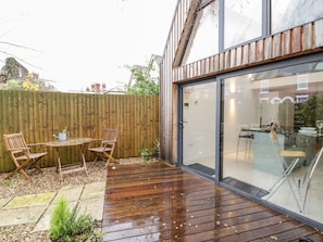 A modern patio with a wooden deck, a table, and two chairs. - Little Mornington (Malvern)