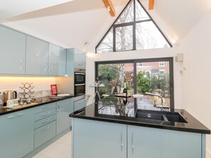 Una cocina moderna con un gran ventanal, horno empotrado y comedor con mesa y sillas.