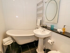 Een badkamer met een bad, een wastafel, een toilet en een spiegel.