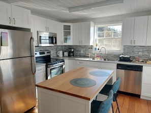 Een moderne keuken met witte kasten, roestvrijstalen apparatuur, een houten eiland en een vaatwasser.