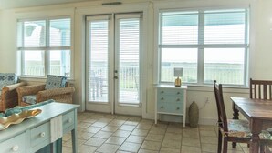 A room with a dining table, chairs, a kitchen counter, and a view through the windows.