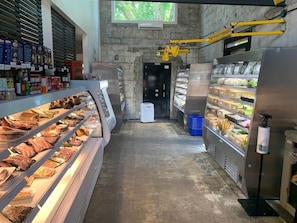 Mostrador de delicatessen con vitrinas de carnes y una sección refrigerada con distintos alimentos.