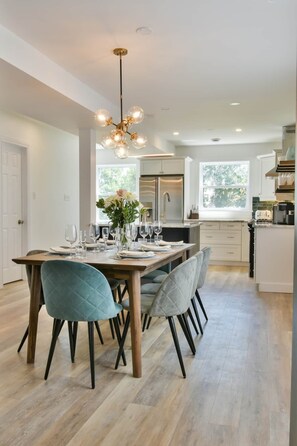 A modern kitchen with a central island, stainless steel appliances, and a dining area with a wooden table and chairs.