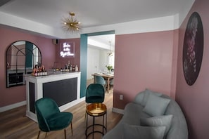 A modern living room with a bar area, a round mirror, and a neon sign. - The Smith - Renovated 4 Bedroom (Prince Edward)