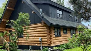 A log cabin with a sloped roof, a satellite dish, and a small porch. - The Log House - Wellington - with Fast Wifi (Wellington)