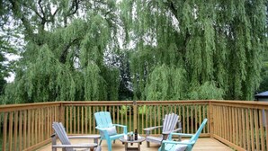 A wooden deck with four light blue Adirondack chairs, a small round table, and a bottle. - The Log House - Wellington - with Fast Wifi (Wellington)