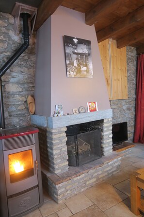 A stone fireplace with a modern stove, a wooden ceiling, and a stone wall. - Chalet in the Tarentaise Valley! Les Belleville  (Saint Jean de Belleville, Les Belleville)