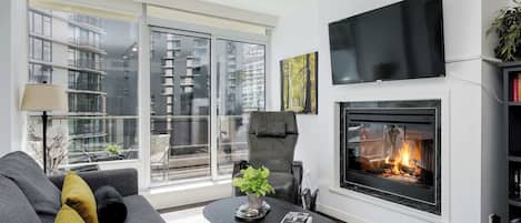 Un salon moderne avec une cheminée, un canapé, une table basse et un téléviseur.