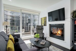 Un salon moderne avec une cheminée, un canapé, une table basse et un téléviseur.