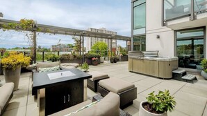 En takterrass med utomhusmöbler, ett område för grillning och krukväxter.