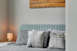 Un dormitorio con pared estampada, cabecero de madera y lámpara de noche.