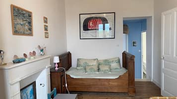 A cozy room with a wooden bed, a small table, a chair, a fireplace, and a wall with framed artwork.
