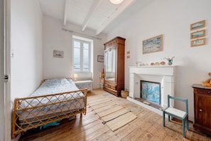A bedroom with a bed, a fireplace, a mirror, and a window.