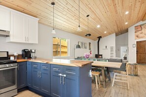 Una cocina moderna con armarios azules, techo de madera y comedor con mesa y sillas.