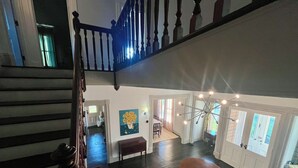Um interior espaçoso com escadaria, área de refeições e uma luminária de teto singular.