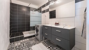 Ein modernes Badezimmer mit Waschmaschine, Waschbecken und Spiegel.