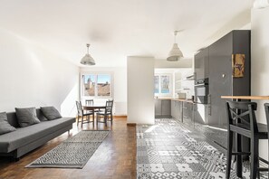 A modern kitchen with dark cabinets, a wooden countertop, and a hanging light fixture. - Large T4 refurbished - 3 bedrooms - Plein Centre (Marseille)