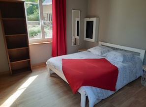A bedroom with a bed, a window with curtains, a TV, and a wooden wardrobe. - Bed and Breakfast 'La Suite Le Moulin' with Shared Terrace, Shared Garden and Air Conditioning (Baugé-en-Anjou)