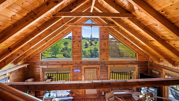 A wooden cabin with a high ceiling, large windows, and a view of a green landscape. - Douglas Lake Log Cabin | Game Room, Big Yard, Sleeps 6 (Sevierville)