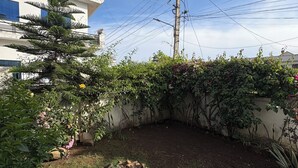 Ein Gartenbereich mit Feuerstelle, umgeben von Grünpflanzen und einem Gebäude im Hintergrund.