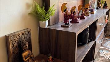 Una estantería de madera con adornos, una estatua de Buda y una planta en maceta.