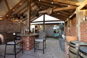 An outdoor patio area with brick walls, wooden beams, and a bar counter. - Rushmoor Retreat, Cosy with Outdoor Pizza Oven (Bratton)