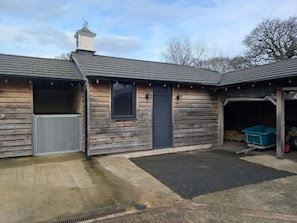 Une construction en bois comprenant un garage, un espace abrité et une allée en béton.