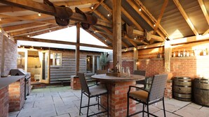 An outdoor patio area with a brick table and chairs, a grill, and wooden barrels.