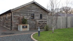 A rustic wooden building with a sloped roof, a gated entrance, and a small planter with a sign.