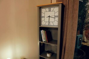 A bookshelf with a clock, books, and a candle.