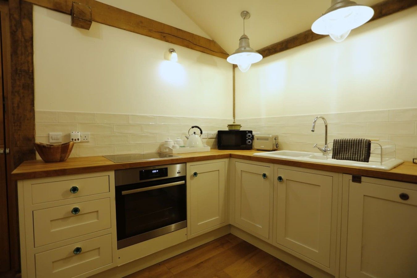 A kitchen with wooden cabinets, a built-in oven, a microwave, a toaster, and a sink with a towel rack.