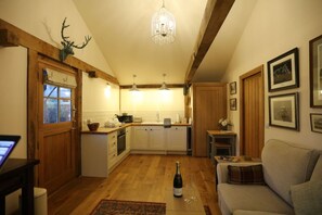 A cozy living room with a fireplace, a dining area, and a kitchen with wooden beams.