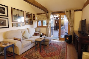 A cozy living room with a sofa, a small table with a bottle, a television, and a fireplace.