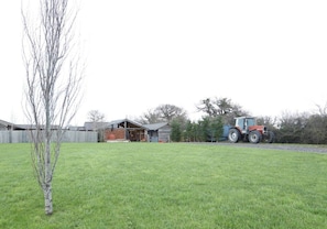 Une propriété rurale avec une grange, une petite maison et un tracteur à l’arrière-plan.