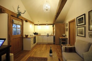 A cozy kitchen with wooden beams, a chandelier, and a dining area with a sofa.