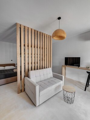 Un dormitorio moderno con sofá, televisión y un separador de madera.