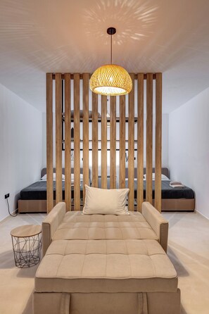 A bedroom with a large bed, a hanging light fixture, and wooden slats on the wall.