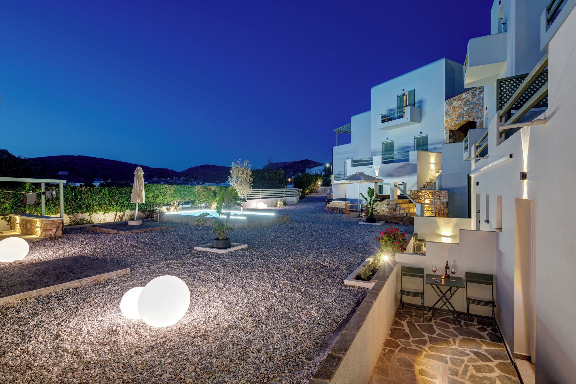 Un edificio moderno con fachada de piedra, mobiliario exterior y zona de piscina.