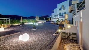A modern building with a stone facade, outdoor seating, and a pool area.