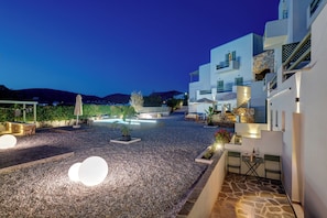 A modern building with a stone facade, outdoor seating, and a pool area.