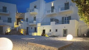 A modern building with multiple balconies, a gravel courtyard, and a large spherical light.