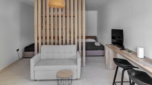A modern room with a sofa, a small round table, a TV, and a wooden partition.