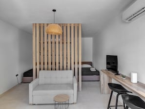 A modern room with a sofa, a small round table, a TV, and a wooden partition.