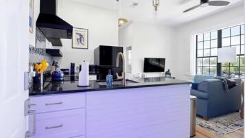 Una cocina moderna con extractor negro, electrodomésticos de acero inoxidable y una isla grande con cajones.
