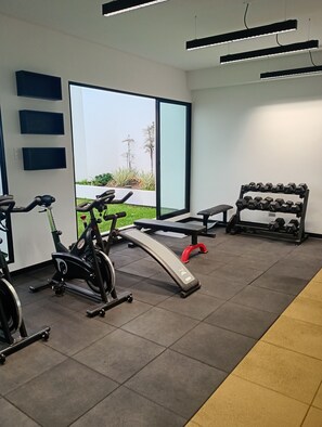 Un gimnasio con equipo de ejercicio, una banca y un soporte para pesas.