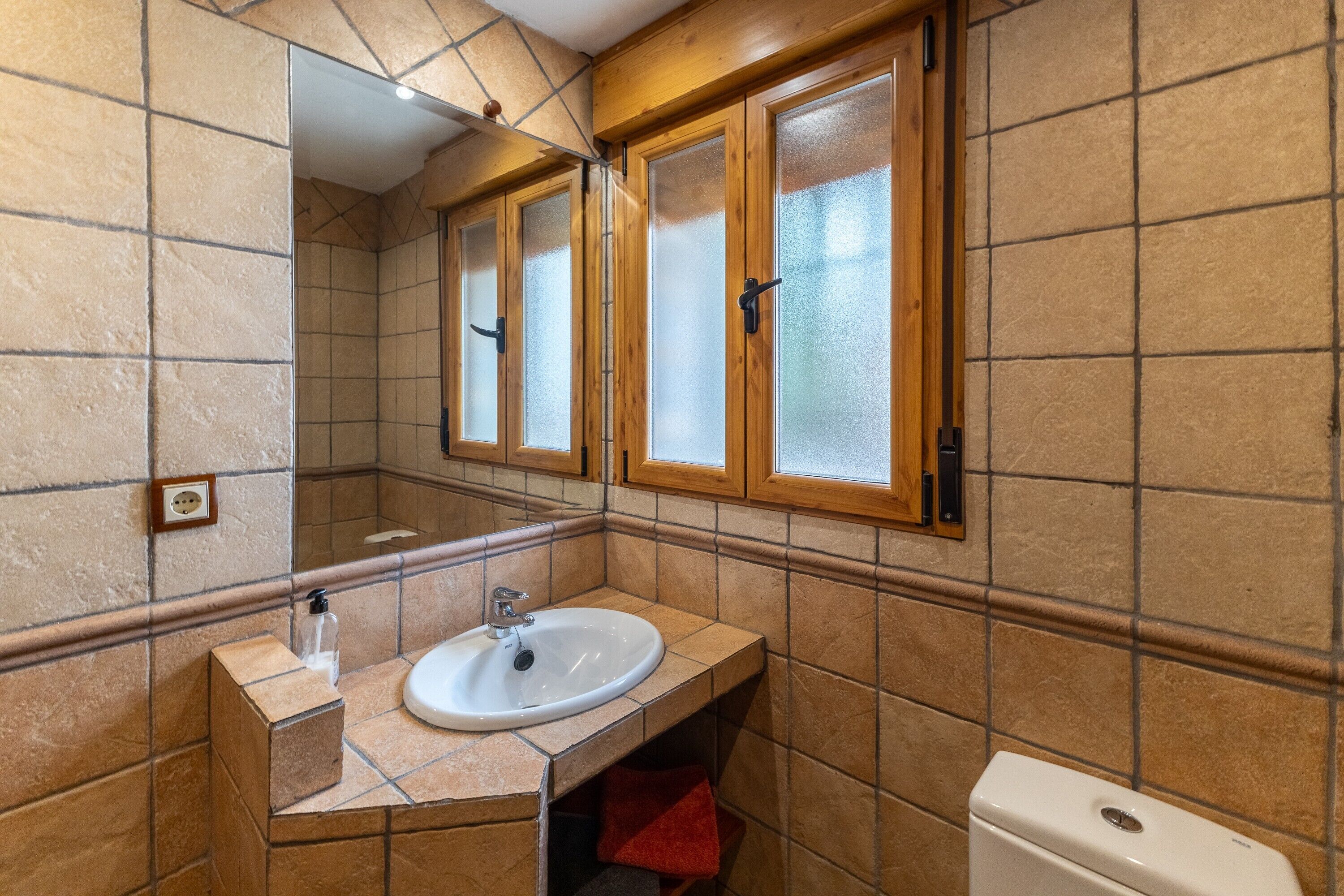 Un bany amb un lavabo, mirall i vàter.